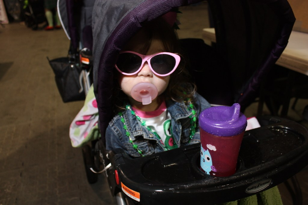 Ein Kind sitzt in einem Walker, der auf der Straße positioniert ist.