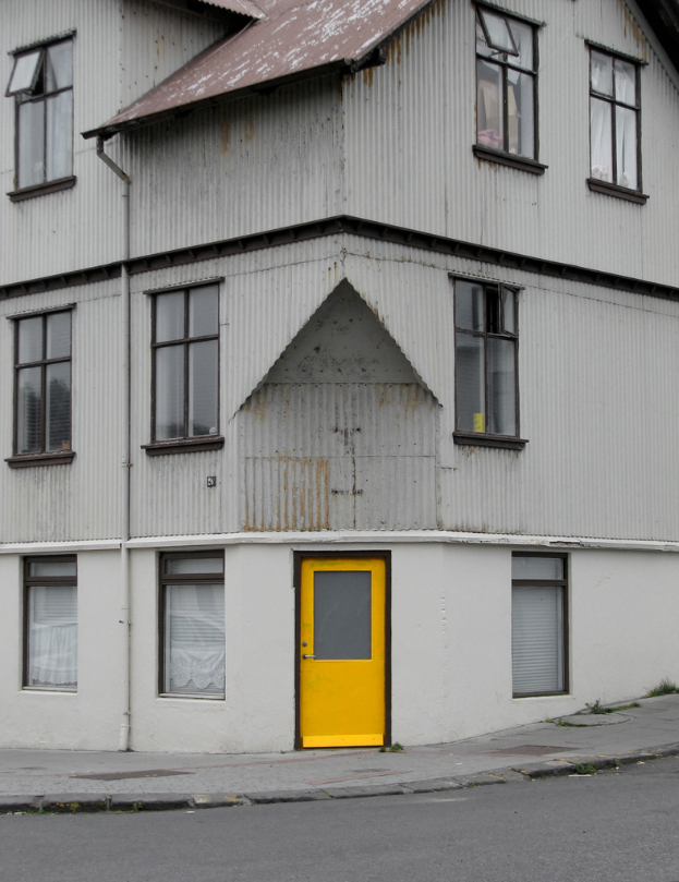 Ein Gebäude mit Glasfenstern und einer gelben Tür, mit einer Straße davor.