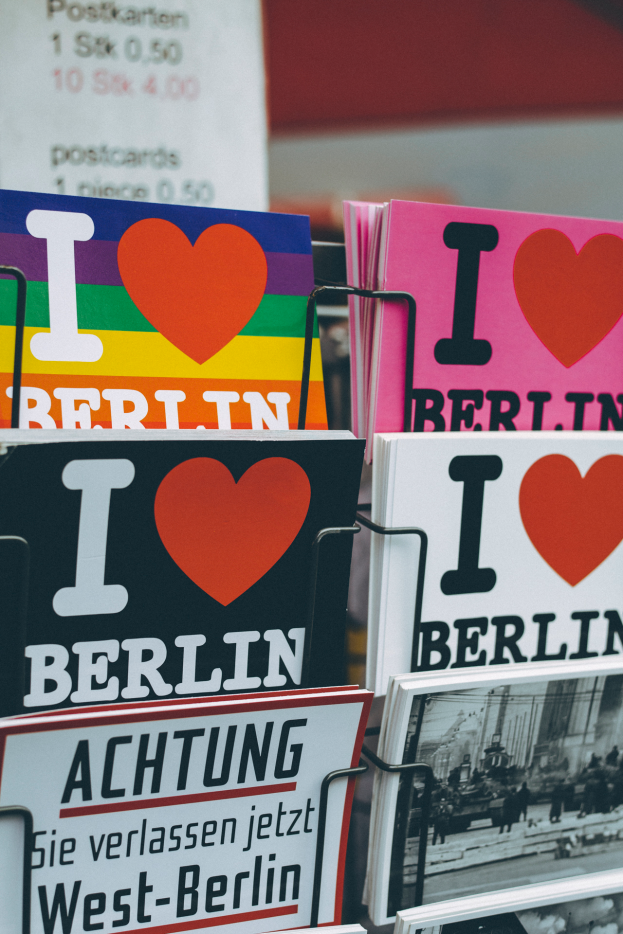 Ein Gestell, auf dem verschiedene Bücher und Plakate mit der Aufschrift "Ich liebe Berlin" in einem leicht unscharfen, träumerischen Setting angeordnet sind.