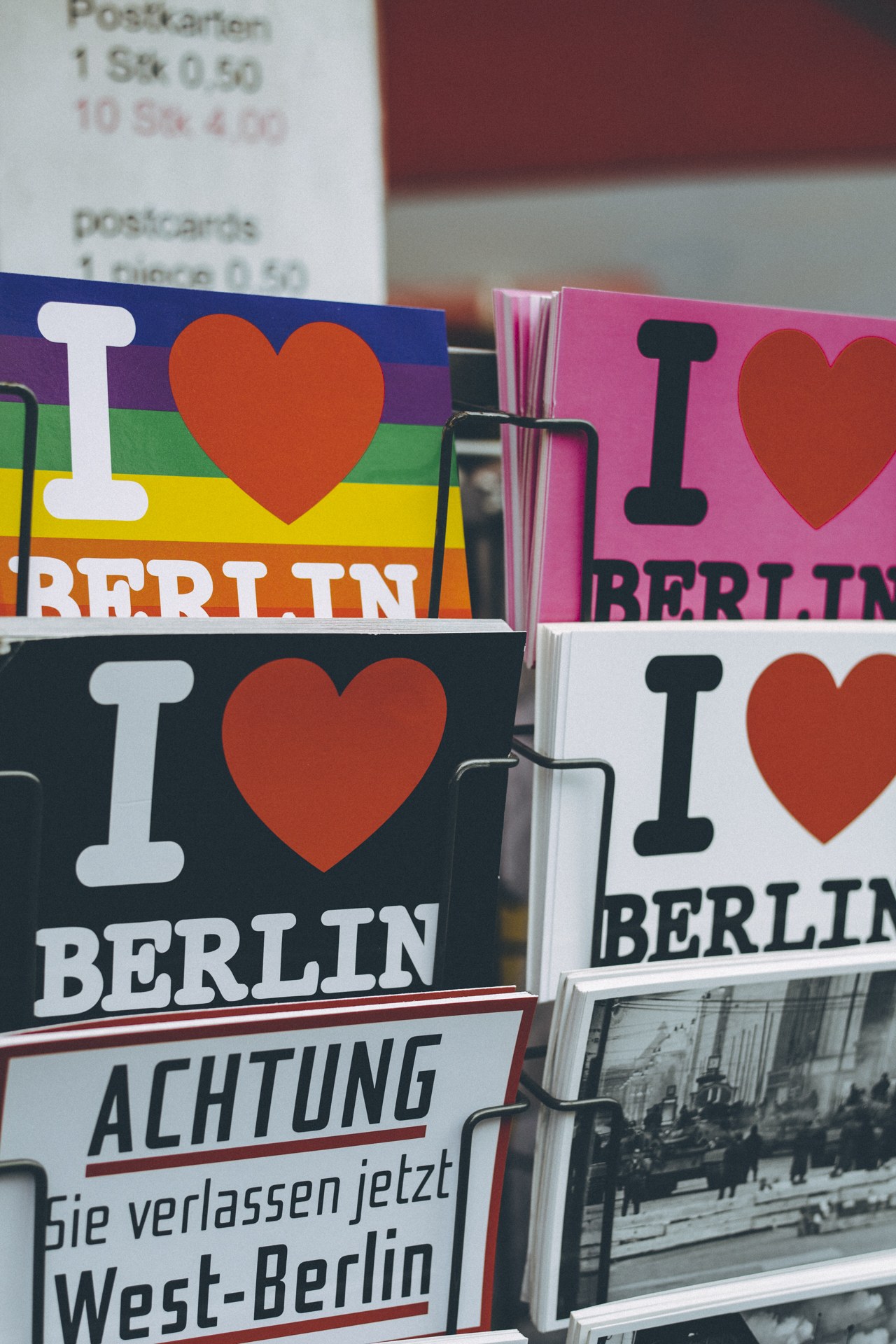 Ein Gestell mit Büchern und Postern mit dem Text "Ich Liebe Berlin", vor einem leicht unscharfen, träumerischen Hintergrund.