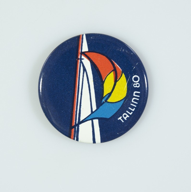 Ein weißer Abzeichen mit einem Segelboot, Text und einer gemalten Segel auf einer weißen Oberfläche.