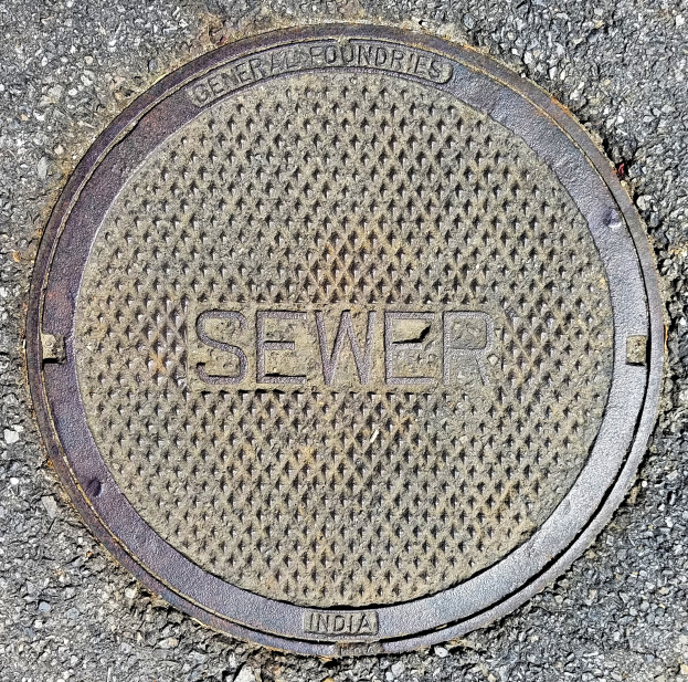 Metallschachtdeckel auf einer Straße mit der Inschrift "Kanal"