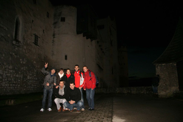 Menschen, die in der Mitte eines Bildes mit einem Schloss im Hintergrund bei Nacht stehen.