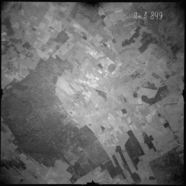 Ein Schwarz-Weiß-Satellitenbild einer Stadt mit zahlreichen Gebäuden und Text oben drauf.
