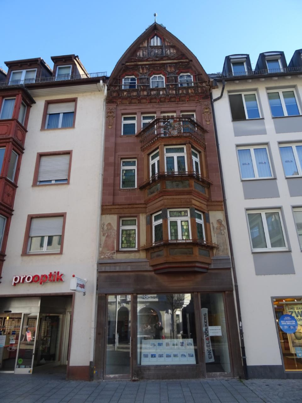 Ein Gewerbegebäude mit zahlreichen Fenstern an der Seite, das sich auf einer Straße in Heidelberg, Deutschland, unter einem klaren blauen Himmel befindet.