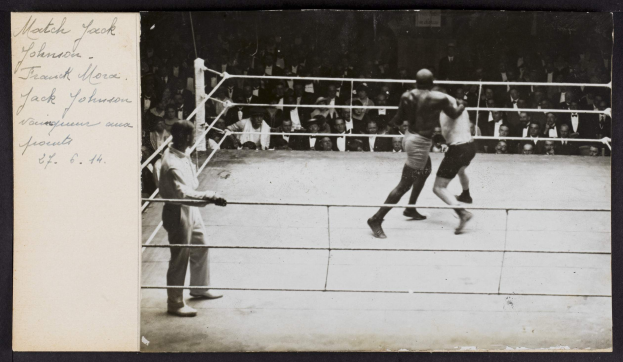 Schwarz-weiß-Foto von zwei Boxern im Ring mit einem Schiedsrichter links und Zuschauern im Hintergrund, beschriftet mit "Jack Johnson vs Frank Morgan".