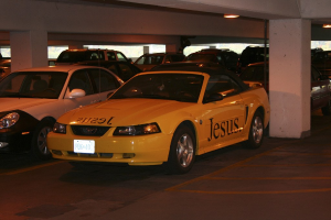 Ein vollgestellter Parkplatz mit zahlreichen geparkten Autos vor einem Gebäude.