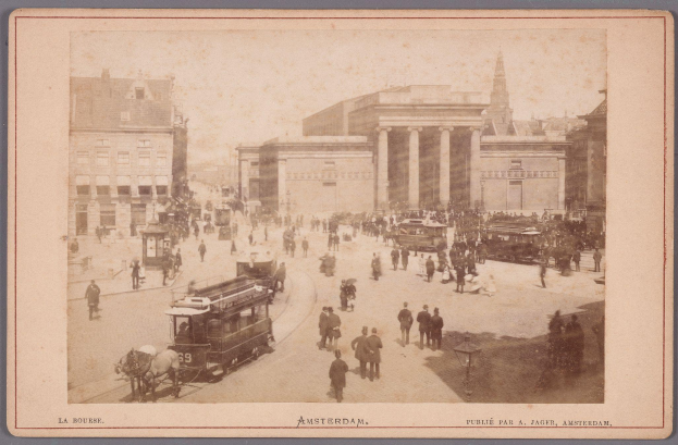 Ein altes Foto einer belebten Amsterdam-Straße mit Menschen, Fahrzeugen, Laternenpfählen und Gebäuden, mit Text am unteren Bildrand.