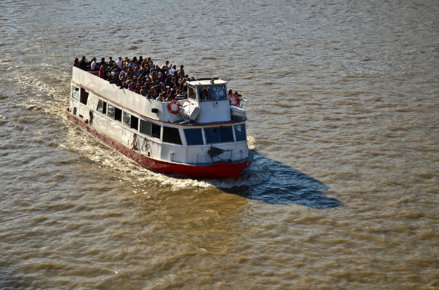 Ein Schiff, das auf dem Wasser segelt, mit vielen Menschen an Deck.