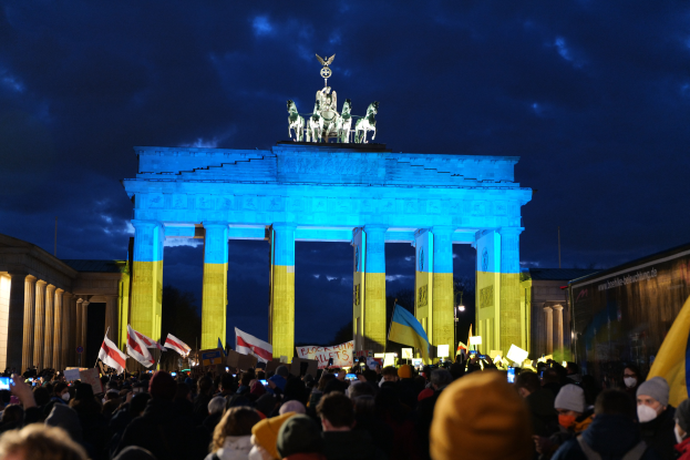 Eine Menschenmenge steht vor dem Brandenburger Tor in Berlin, Deutschland, mit Fahnen und Plakaten, mit einer Banner auf der rechten Seite.