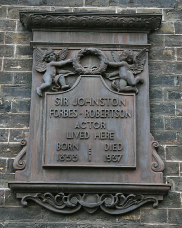 Eine Statue an einer Wand mit eingraviertem Text.