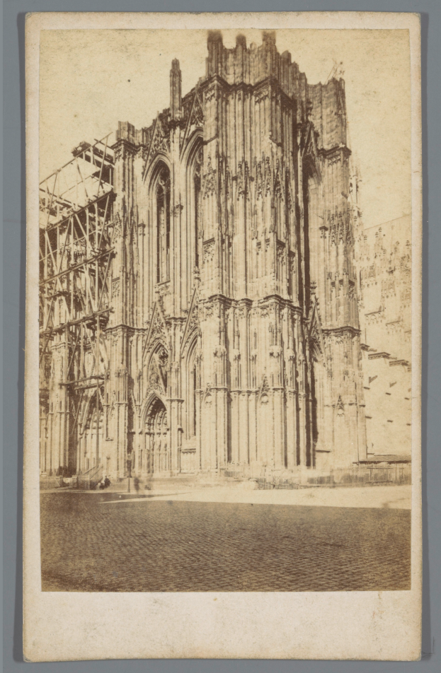 Ein Schwarz-Weiß-Foto einer großen, fensterreichen Kathedrale mit detaillierten Verzierungen vor einem grauen Hintergrund.