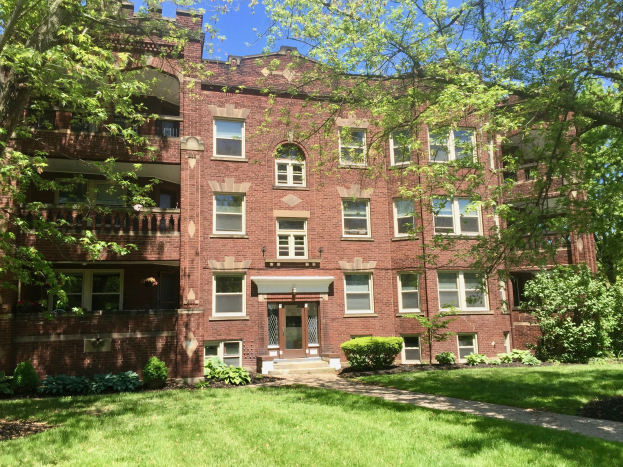 Großes Backsteingebäude mit einem grünen Rasen, Bäumen und Pflanzen davor, unter einem klaren blauen Himmel, gelegen in Chicago, Illinois.