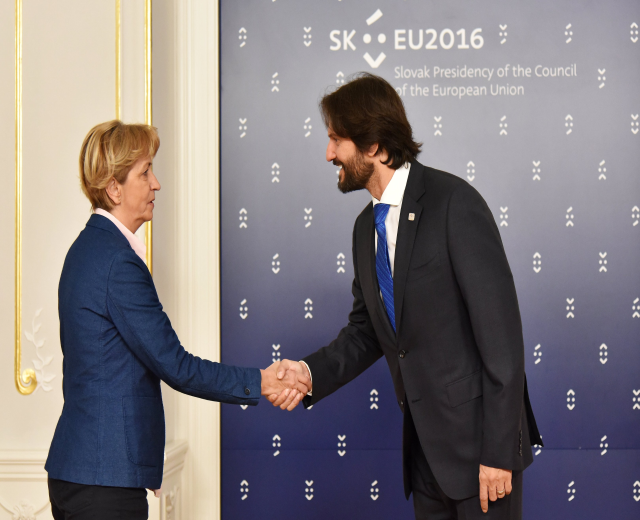 Bundeskanzlerin Angela Merkel und Bundespräsident Joachim Gauck schütteln sich die Hände vor einem "EU-Gipfel"-Plakat, beide lächeln.
