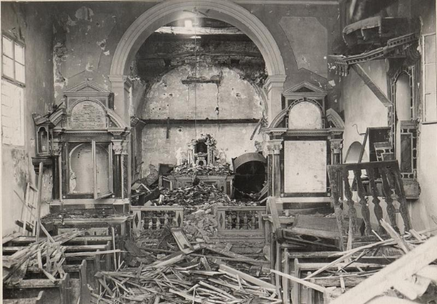 Ein altes Schwarz-Weiß-Foto eines feuergeschädigten Kircheninneren mit verstreuten Holztrümmern und Fenstern auf beiden Seiten.