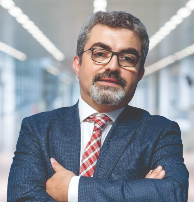 Ein Mann im Anzug mit verschränkten Armen und Brille steht vor einem unscharfen Hintergrund, identifiziert als neuer Marketingchef durch Text unten.