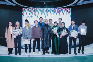 Gruppe von Menschen auf einer Bühne mit Blumensträußen und Urkunden, mit einem "Jugend Solar Awards 2019"-Plakat im Hintergrund.