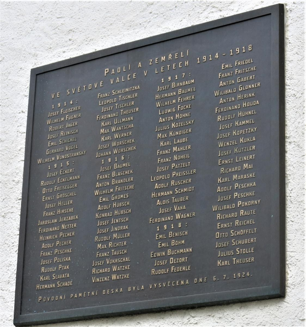 Plaque an einer Gebäudewand mit der Inschrift "Plaque für die Opfer des Holocaust" in fetter Schrift, umgeben von einem dekorativen Rahmen, aus dunklem Material hergestellt.