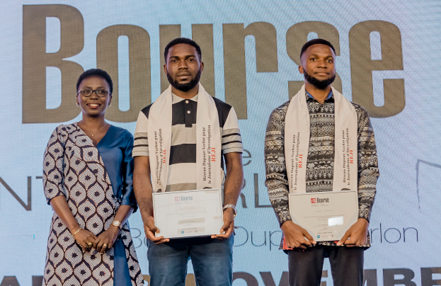 Drei Personen auf einer Bühne mit Urkunden in den Händen und einem Hintergrundbild mit der Aufschrift "Bounce Africa Awards 2019."
