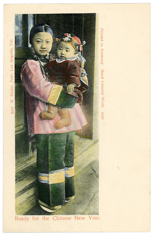 Eine alte Postkarte mit einer Frau, die ein Baby im Arm hält und beide fröhlich in die Kamera schauen.