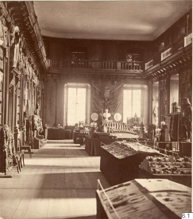 Schwarz-weiß-Foto eines Raums im Museum of Fine Arts, London, voller Tische, Stühle, Skulpturen an den Wänden, Fenstern, Vorhängen und Geländern.