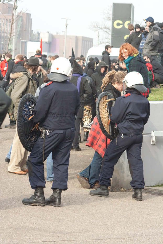 Eine Gruppe von Menschen, die auf einer Stra{\ss}e gehen, mit zwei Personen in der Vornahme, die wie Polizei aussehen, Geb"ude im Hintergrund und Boden unten.